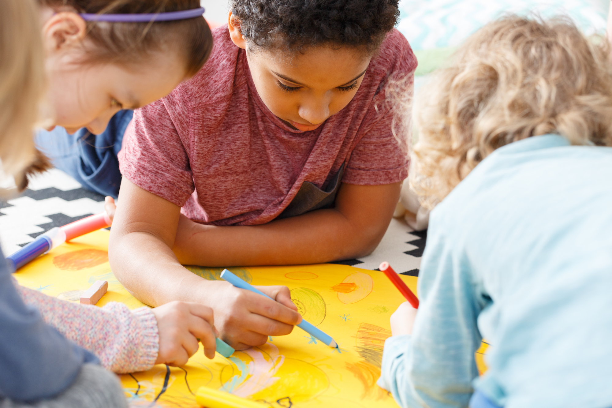 Kids laying on the floor coloring together